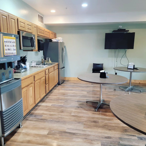 Staff break room with oak cabinetry and round tables